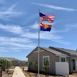 Newly installed aluminum flagpole with the American and Arizona flags flying by house