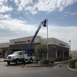flagpole being installed in front of a Bank of America with work truck and worker