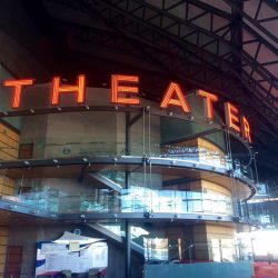 Red Neon Theater sign on glass under awning